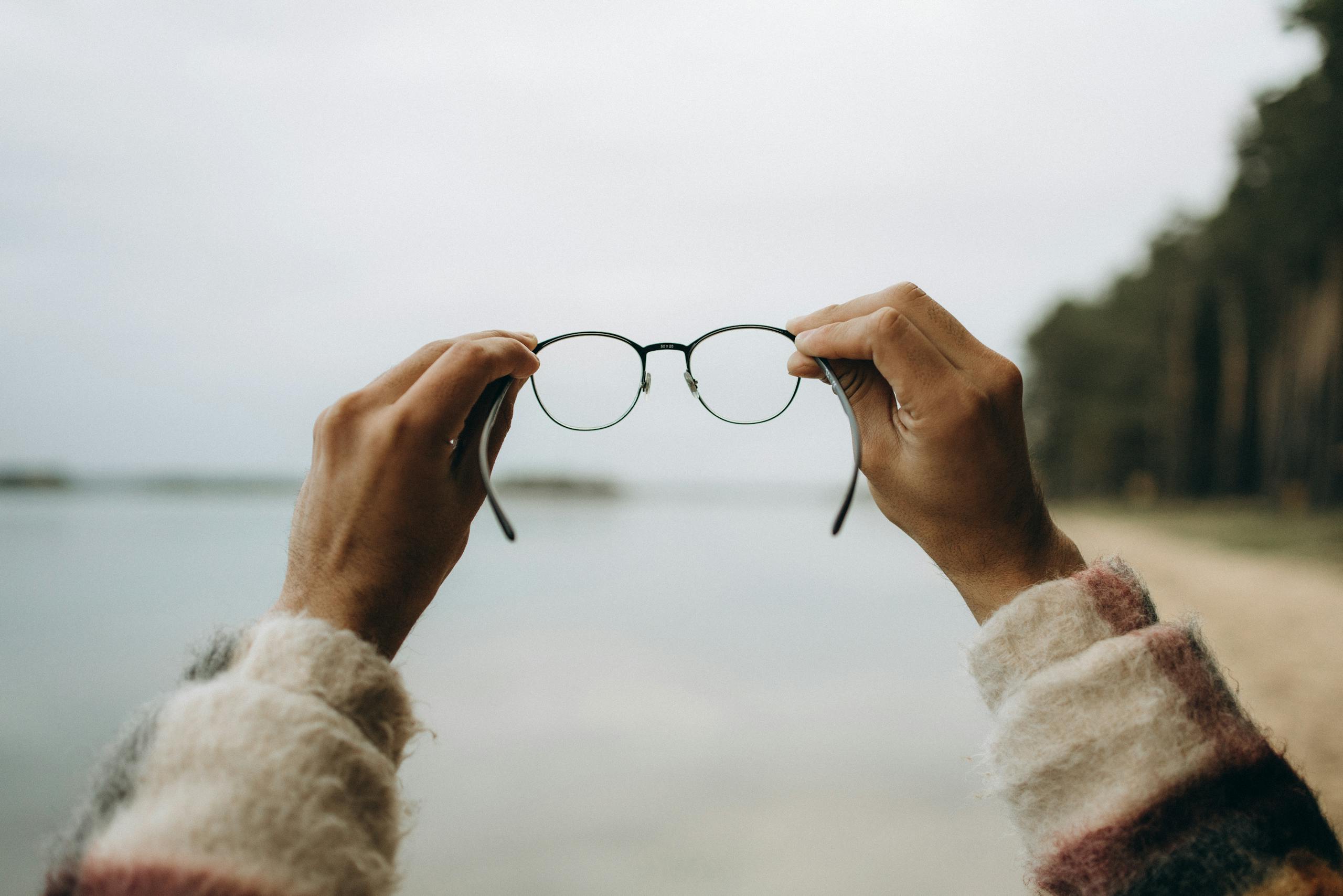 Hands holding blurred eyeglasses symbolizing vision loss from Elmiron usage undergoing a Elmrion lawsuit