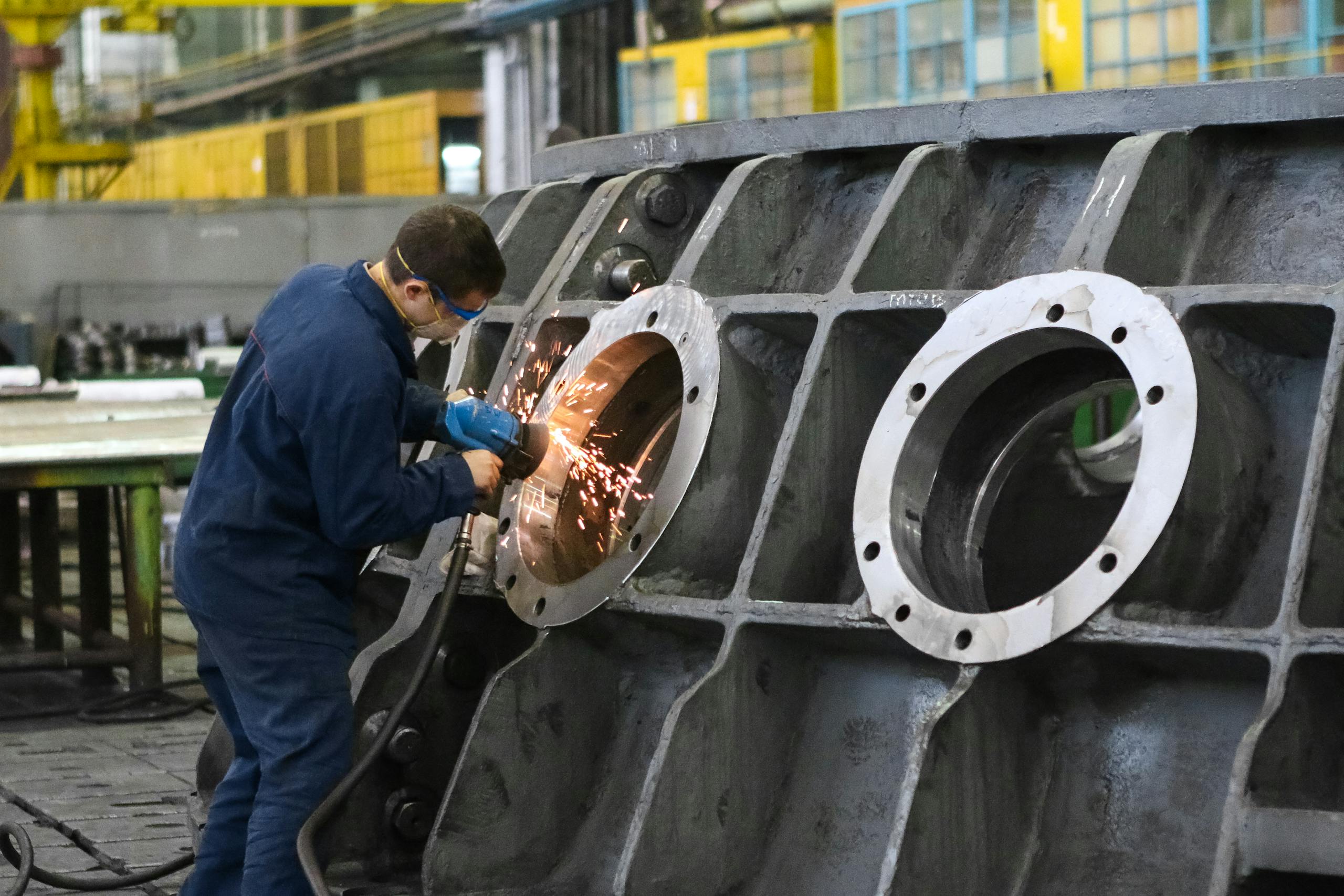 Can I sue for asbestos exposure - worker grinding large industrial machinery, showing asbestos exposure risks in manufacturing and shipyard jobs
