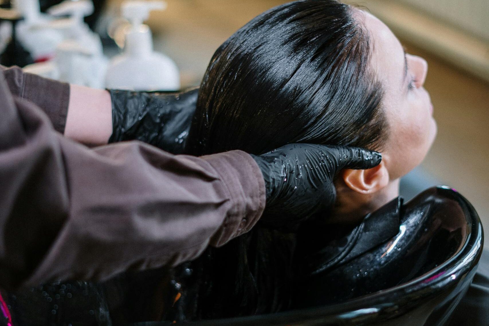 Hair stylist applying chemical relaxer treatment to woman's hair in salon, representing product liability lawsuit