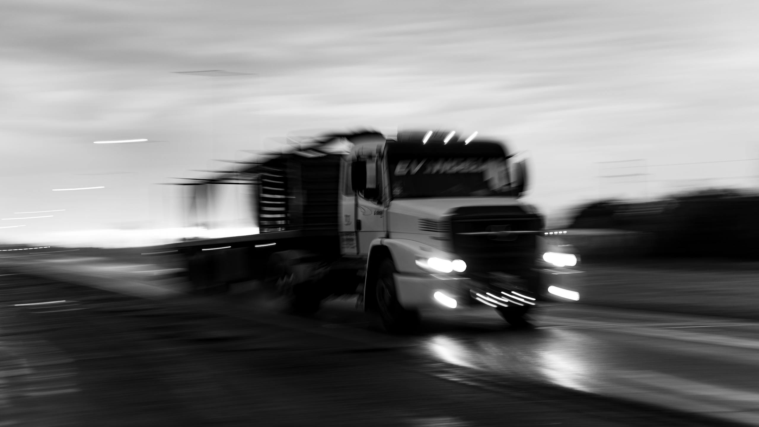 Texas truck accident lawyer - Dynamic black and white photo depicting a moving truck on a rainy road, creating a dramatic blur effect.